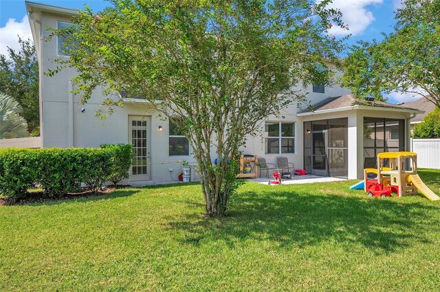 10833 Breaking Rocks Dr, Tampa, FL 33647 - rear view of house with a yard, a sunroom, stucco siding, and a patio area