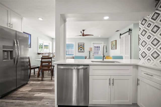 2479 Trade Winds Dr, Dunedin, FL 34698 - kitchen with stainless steel appliances, a sink, a barn door, a peninsula, and dark wood finished floors