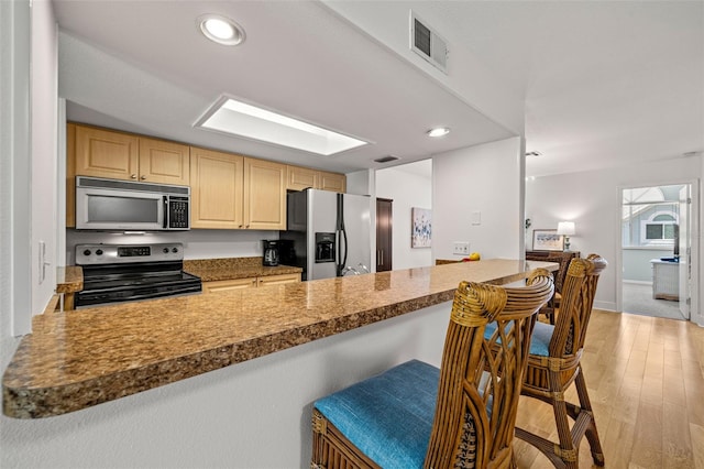 616 Garland Cir, Indian Rocks Beach, FL 33785 - kitchen featuring appliances with stainless steel finishes, a kitchen bar, a peninsula, light wood-style floors, and recessed lighting