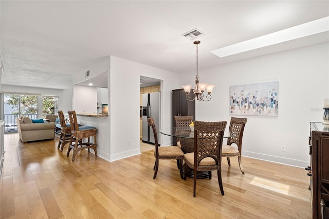 616 Garland Cir, Indian Rocks Beach, FL 33785 - dining room featuring light wood-style flooring, baseboards, a chandelier, and a skylight