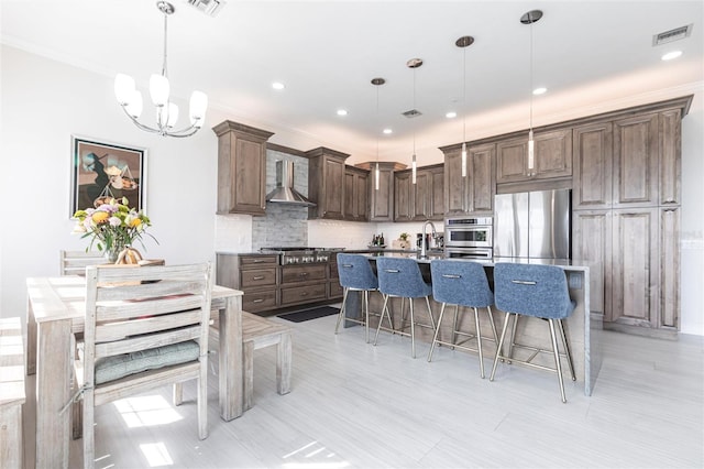 24197 Treasure Island Blvd, Punta Gorda, FL 33955 - kitchen featuring appliances with stainless steel finishes, wall chimney exhaust hood, a kitchen bar, a chandelier, and a kitchen island with sink