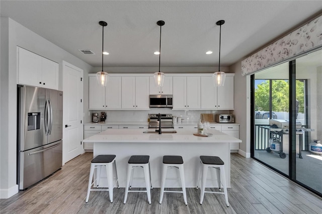 72031/2 S W Shore Blvd, Tampa, FL 33616 - kitchen with stainless steel appliances, light wood-style floors, a sink, a kitchen bar, and recessed lighting