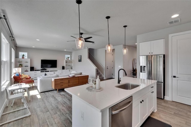 72031/2 S W Shore Blvd, Tampa, FL 33616 - kitchen with appliances with stainless steel finishes, a sink, light wood finished floors, white cabinetry, and pendant lighting