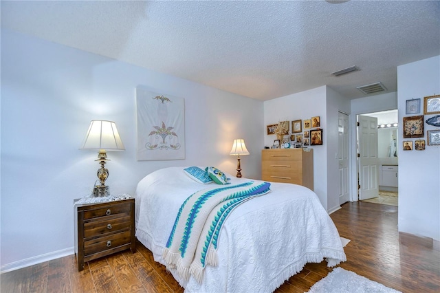 1210 Wolford Dr, Trinity, FL 34655 - bedroom featuring wood finished floors, baseboards, a textured ceiling, and ensuite bathroom