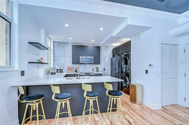 215 Central Ave Unit 2B, Saint Petersburg, FL 33701 - kitchen featuring estacked washer and dryer, open shelves, stainless steel microwave, light countertops, and a breakfast bar