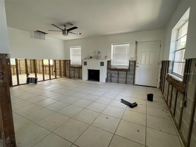 3207 S De Bazan Ave, St Pete Beach, FL 33706 - unfurnished living room with ceiling fan, tile patterned flooring, plenty of natural light, and a fireplace