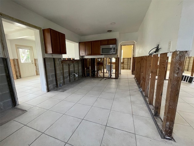 3207 S De Bazan Ave, St Pete Beach, FL 33706 - kitchen with stainless steel microwave, light tile patterned floors, and a wainscoted wall