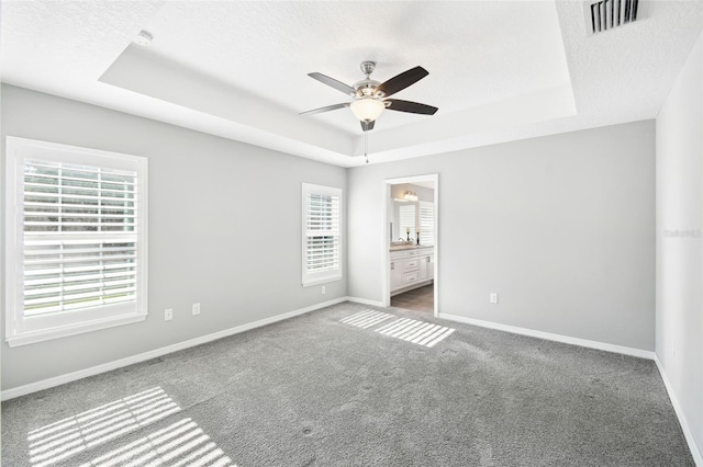 13227 Quigley Ave, Weeki Wachee, FL 34614 - unfurnished bedroom featuring a raised ceiling, carpet flooring, baseboards, ensuite bathroom, and a textured ceiling