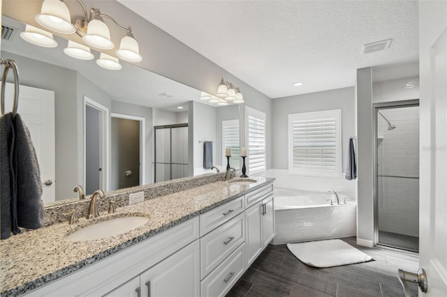 13227 Quigley Ave, Weeki Wachee, FL 34614 - bathroom featuring a shower stall, a garden tub, double vanity, wood finish floors, and a textured ceiling