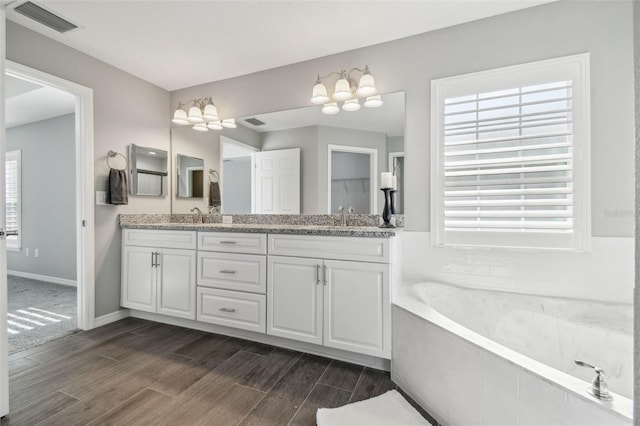 13227 Quigley Ave, Weeki Wachee, FL 34614 - bathroom with double vanity, a garden tub, wood finished floors, baseboards, and a chandelier