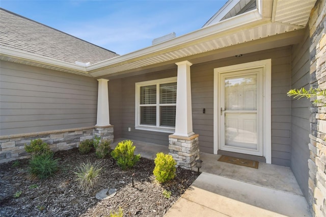 13227 Quigley Ave, Weeki Wachee, FL 34614 - view of exterior entry with a porch, a shingled roof, and stone siding