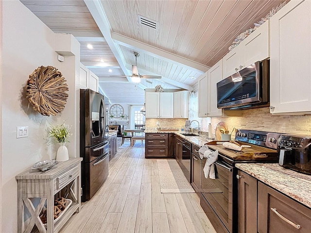 1445 Stonehenge Way, Palm Harbor, FL 34683 - kitchen with black appliances, a sink, white cabinets, tasteful backsplash, and light wood-style floors