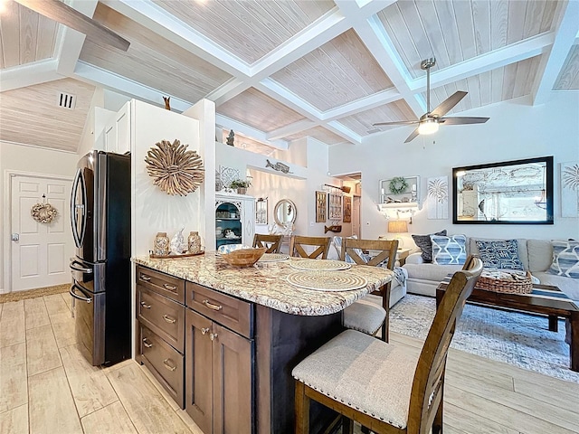 1445 Stonehenge Way, Palm Harbor, FL 34683 - kitchen featuring freestanding refrigerator, a breakfast bar area, light wood-type flooring, open floor plan, and beam ceiling
