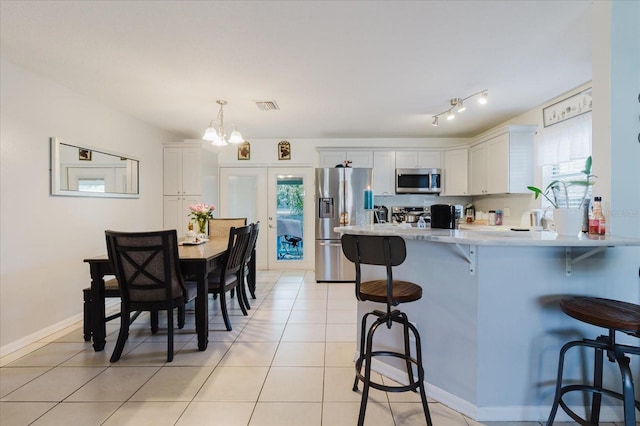 8517 N Branch Ave, Tampa, FL 33604 - kitchen with stainless steel appliances, a breakfast bar, a peninsula, light countertops, and a chandelier