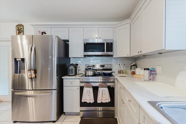 8517 N Branch Ave, Tampa, FL 33604 - kitchen featuring appliances with stainless steel finishes, tasteful backsplash, light tile patterned floors, and white cabinetry