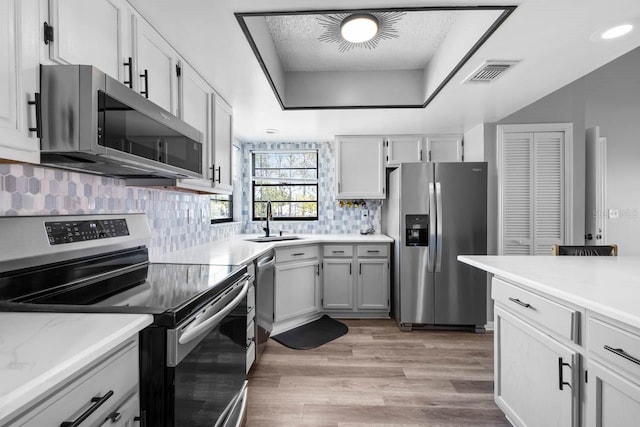 609 Lively Dr Unit B, Sun City Center, FL 33573 - kitchen with stainless steel appliances, a sink, backsplash, light wood-style floors, and light countertops