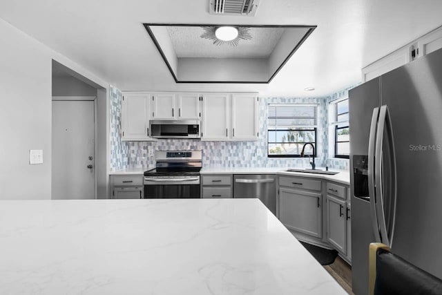 609 Lively Dr Unit B, Sun City Center, FL 33573 - kitchen featuring appliances with stainless steel finishes, a sink, backsplash, gray cabinetry, and light stone counters