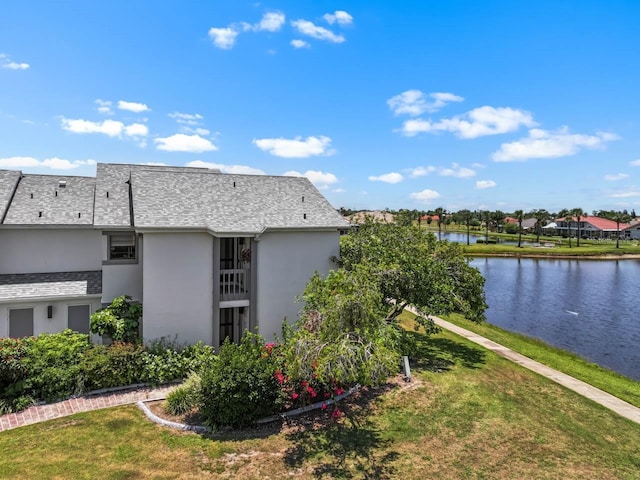 609 Lively Dr Unit B, Sun City Center, FL 33573 - view of property exterior featuring stucco siding, a yard, a water view, and a shingled roof