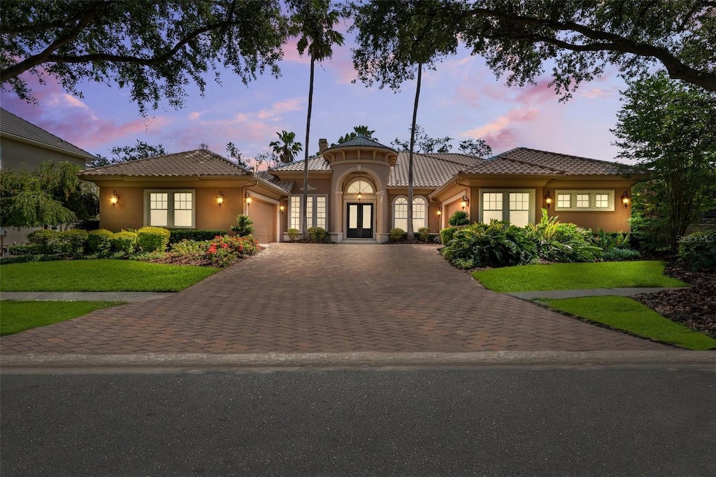 15110 Kestrelglen Way, Lithia, FL 33547 - mediterranean / spanish home featuring an attached garage, french doors, stucco siding, decorative driveway, and a tile roof
