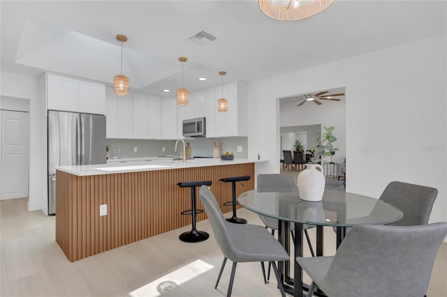 323 48th St NW, Bradenton, FL 34209 - kitchen featuring appliances with stainless steel finishes, a peninsula, light countertops, white cabinetry, and recessed lighting