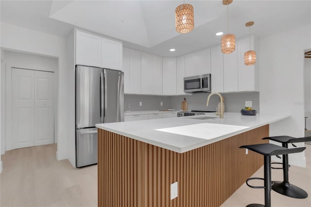 323 48th St NW, Bradenton, FL 34209 - kitchen with stainless steel appliances, a peninsula, a kitchen breakfast bar, decorative backsplash, and white cabinets