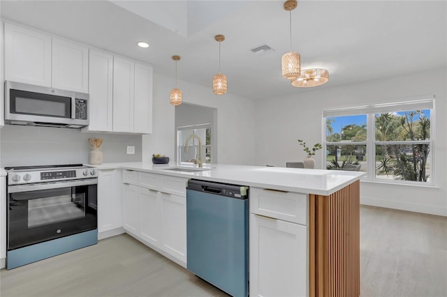 323 48th St NW, Bradenton, FL 34209 - kitchen with stainless steel appliances, a sink, light wood-style floors, a peninsula, and recessed lighting