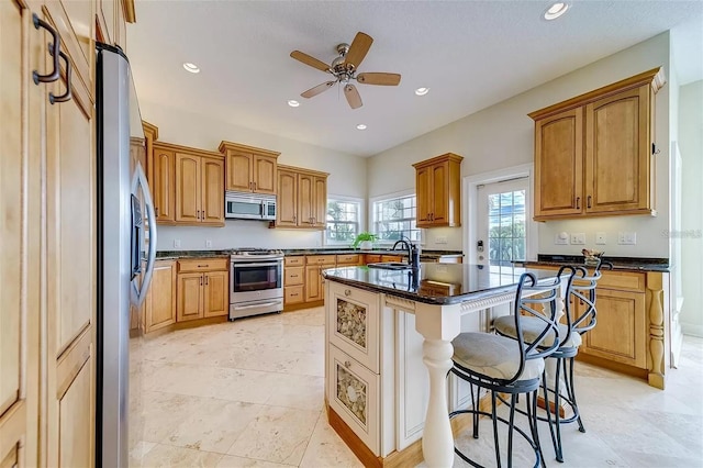 803 Harbor Dr, Belleair Beach, FL 33786 - kitchen with appliances with stainless steel finishes, a sink, a breakfast bar area, ceiling fan, and a kitchen island with sink