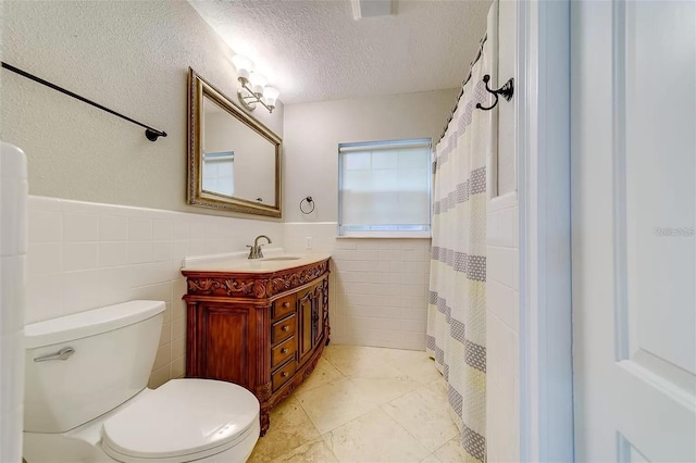 803 Harbor Dr, Belleair Beach, FL 33786 - full bathroom with tile walls, a textured ceiling, vanity, wainscoting, and toilet