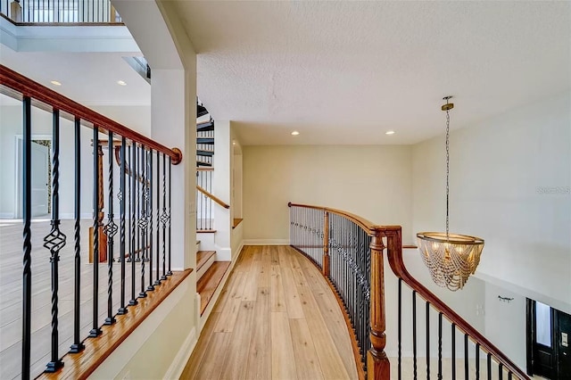 803 Harbor Dr, Belleair Beach, FL 33786 - hall featuring a chandelier, wood finished floors, an upstairs landing, baseboards, and a textured ceiling