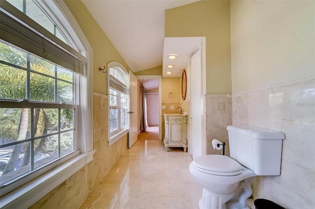 803 Harbor Dr, Belleair Beach, FL 33786 - bathroom featuring tile walls, marble tiled floors, lofted ceiling, toilet, and wainscoting