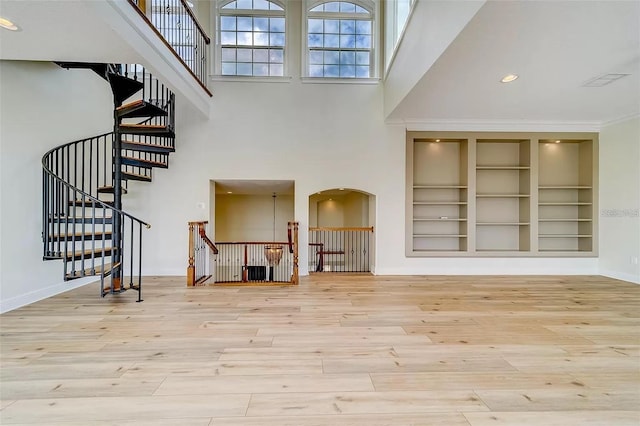 803 Harbor Dr, Belleair Beach, FL 33786 - unfurnished living room featuring wood finished floors, a high ceiling, built in shelves, baseboards, and arched walkways