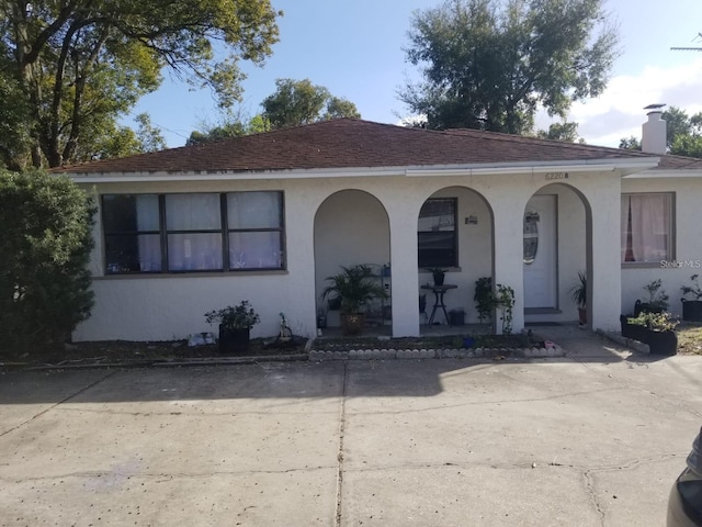 6220 Massachusetts Ave, New Port Richey, FL 34653 - view of front of home with a porch, stucco siding, uncovered parking, and a chimney