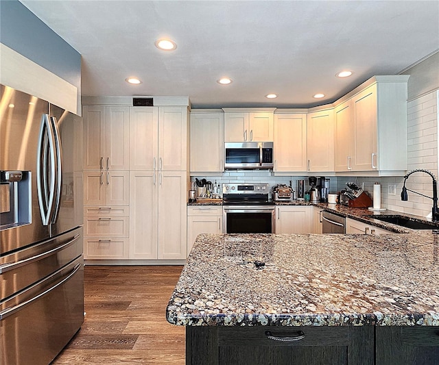 1608 20th Ave W, Palmetto, FL 34221 - kitchen with appliances with stainless steel finishes, a sink, dark stone counters, decorative backsplash, and recessed lighting