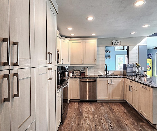 1608 20th Ave W, Palmetto, FL 34221 - kitchen with stainless steel appliances, a sink, a peninsula, dark wood-type flooring, and dark stone countertops