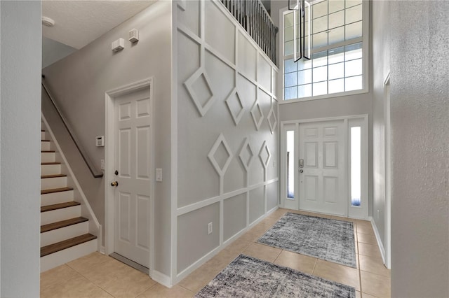 7732 Bulls Head Dr, Wesley Chapel, FL 33545 - foyer entrance featuring light tile patterned flooring, a high ceiling, stairway, and baseboards