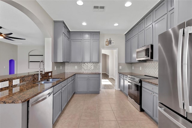 7732 Bulls Head Dr, Wesley Chapel, FL 33545 - kitchen featuring stainless steel appliances, a sink, gray cabinetry, dark stone counters, and a peninsula