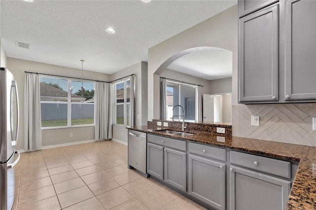 7732 Bulls Head Dr, Wesley Chapel, FL 33545 - kitchen with stainless steel appliances, gray cabinetry, a sink, arched walkways, and tasteful backsplash