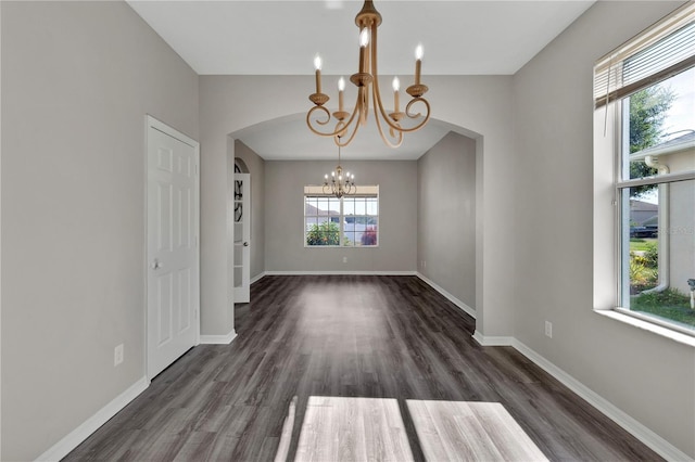 7732 Bulls Head Dr, Wesley Chapel, FL 33545 - empty room with a chandelier, arched walkways, dark wood-style flooring, and baseboards