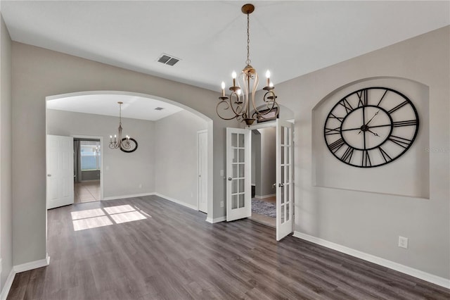 7732 Bulls Head Dr, Wesley Chapel, FL 33545 - unfurnished dining area featuring a chandelier, arched walkways, dark wood-type flooring, baseboards, and french doors