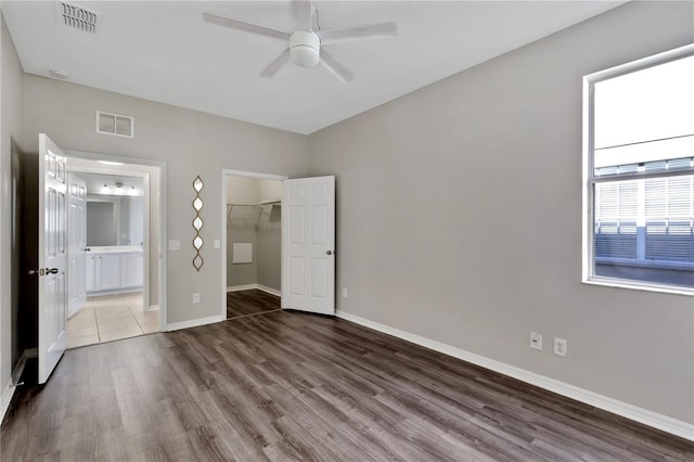 7732 Bulls Head Dr, Wesley Chapel, FL 33545 - unfurnished bedroom featuring wood finished floors, baseboards, a walk in closet, ensuite bath, and a closet