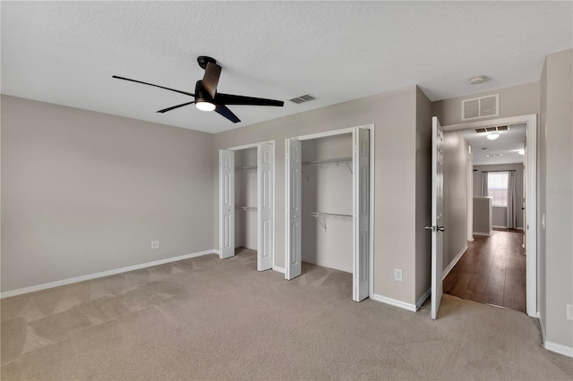 7732 Bulls Head Dr, Wesley Chapel, FL 33545 - unfurnished bedroom featuring two closets, carpet floors, baseboards, a textured ceiling, and a ceiling fan