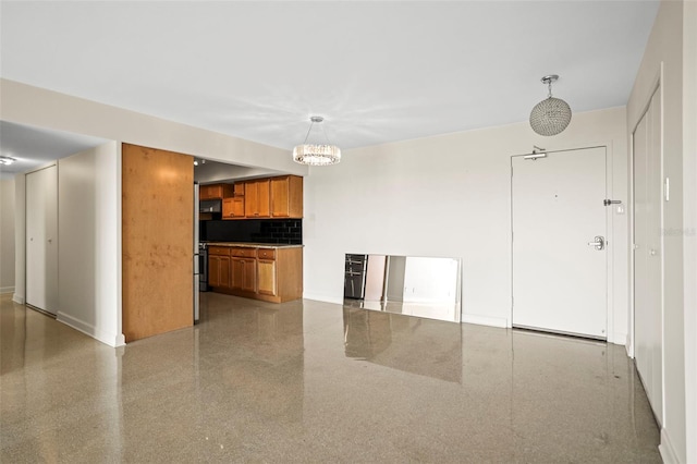10355 Paradise Blvd Unit 1003, Treasure Island, FL 33706 - kitchen with brown cabinets, backsplash, a chandelier, baseboards, and decorative light fixtures