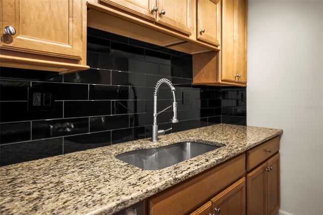 10355 Paradise Blvd Unit 1003, Treasure Island, FL 33706 - kitchen with tasteful backsplash, a sink, light stone countertops, and brown cabinets