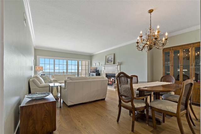 1586 Gulf Blvd Unit 2502, Clearwater, FL 33767 - dining room featuring crown molding, a glass covered fireplace, a chandelier, and wood finished floors