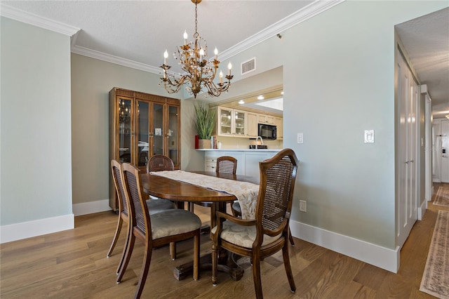 1586 Gulf Blvd Unit 2502, Clearwater, FL 33767 - dining room featuring a chandelier, baseboards, crown molding, and wood finished floors