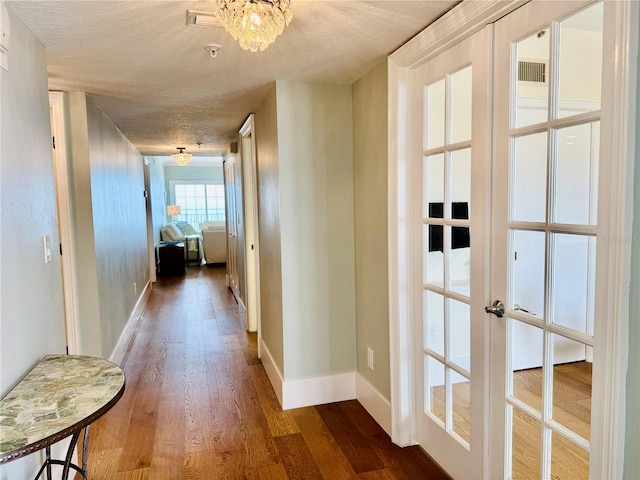 1586 Gulf Blvd Unit 2502, Clearwater, FL 33767 - hall with dark wood-type flooring, a textured ceiling, french doors, and a chandelier