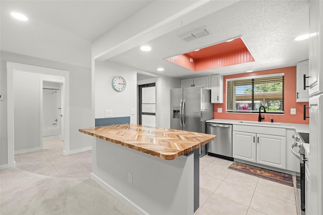 2510 Laurelwood Dr Unit 5B, Clearwater, FL 33763 - kitchen featuring stainless steel appliances, a sink, wood counters, light tile patterned floors, and white cabinets