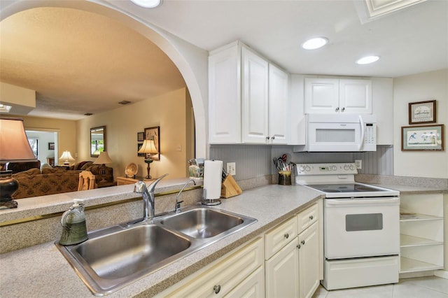 3476 Tarpon Woods Blvd, Palm Harbor, FL 34685 - kitchen featuring white appliances, a sink, arched walkways, light countertops, and white cabinets