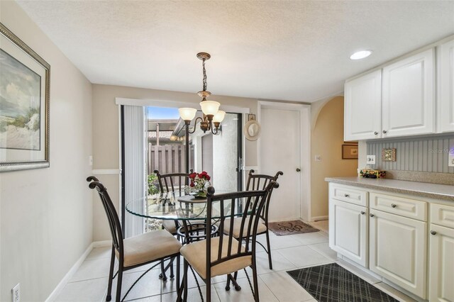 3476 Tarpon Woods Blvd, Palm Harbor, FL 34685 - dining room with arched walkways, a chandelier, light tile patterned flooring, and baseboards