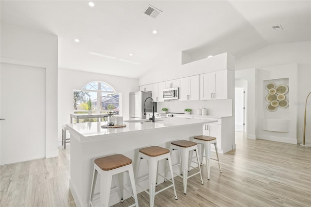 10538 Juliano Dr, Riverview, FL 33569 - kitchen featuring appliances with stainless steel finishes, lofted ceiling, an island with sink, a breakfast bar, and light countertops